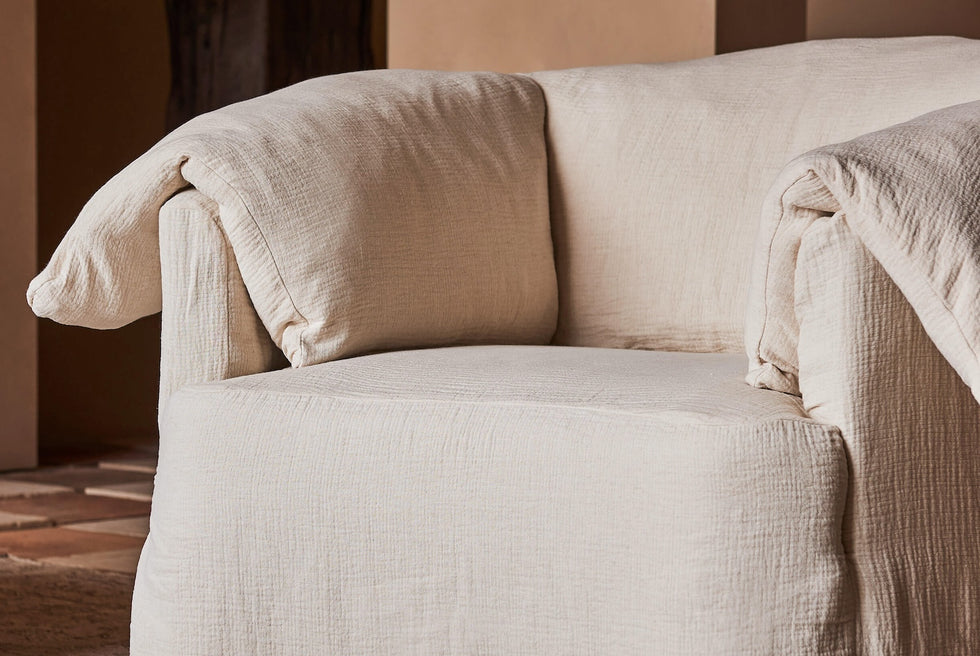 Close up of Loula Swivel Chair in Corn Silk Washed Cotton Linen, placed in a warmly lit room