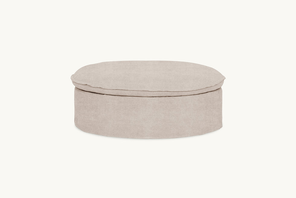 Side view of Neva Round Storage Ottoman in Oat Flour, a medium taupe Light Weight Linen