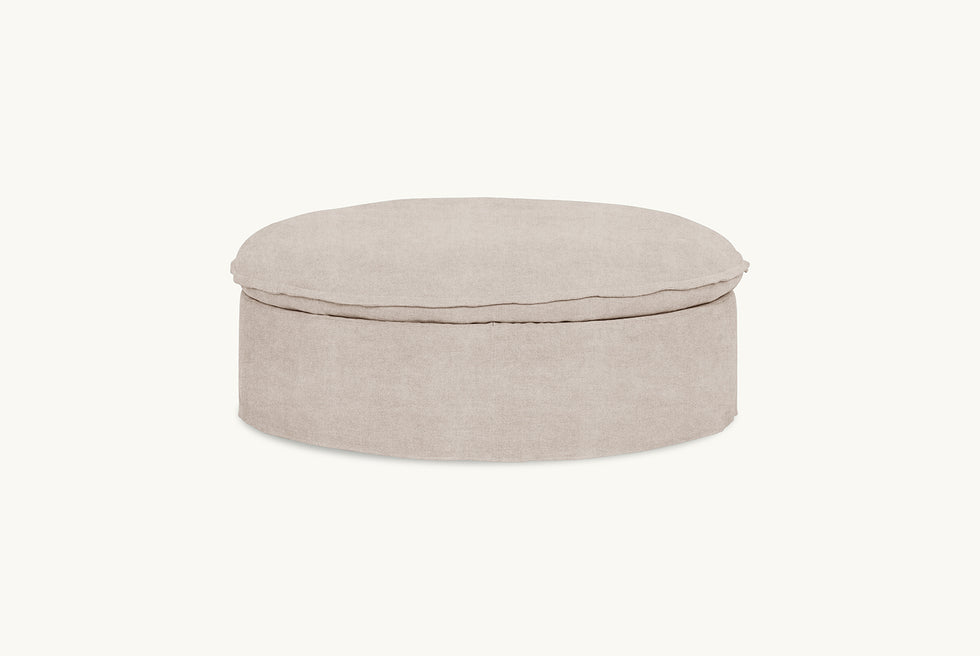 Side view of Neva Round Storage Ottoman in Oat Flour, a medium taupe Light Weight Linen