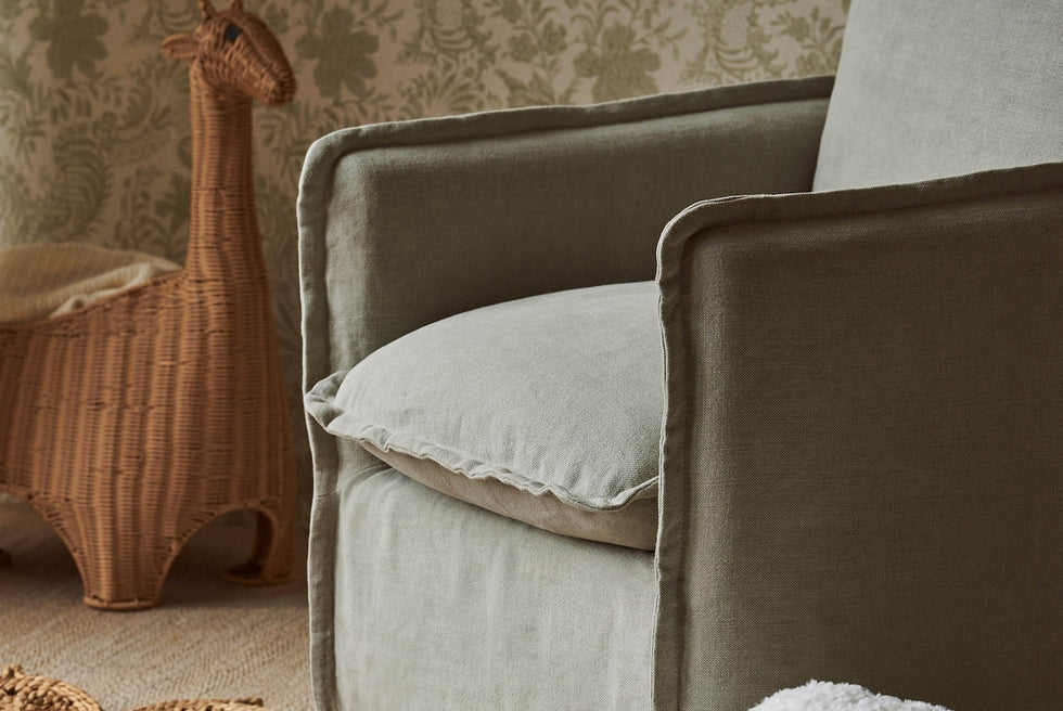 Close up of Neva Swivel Glider Chair in Jasmine Rice, a light warm greige Medium Weight Linen placed in a nursery decorated room