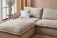 Slide #6 Close up of Neva U-Shape Sectional Sofa in Jasmine Rice, a light warm greige Medium Weight Linen, placed in a well-lit room with white throw pillows, next to a plant on a stool.