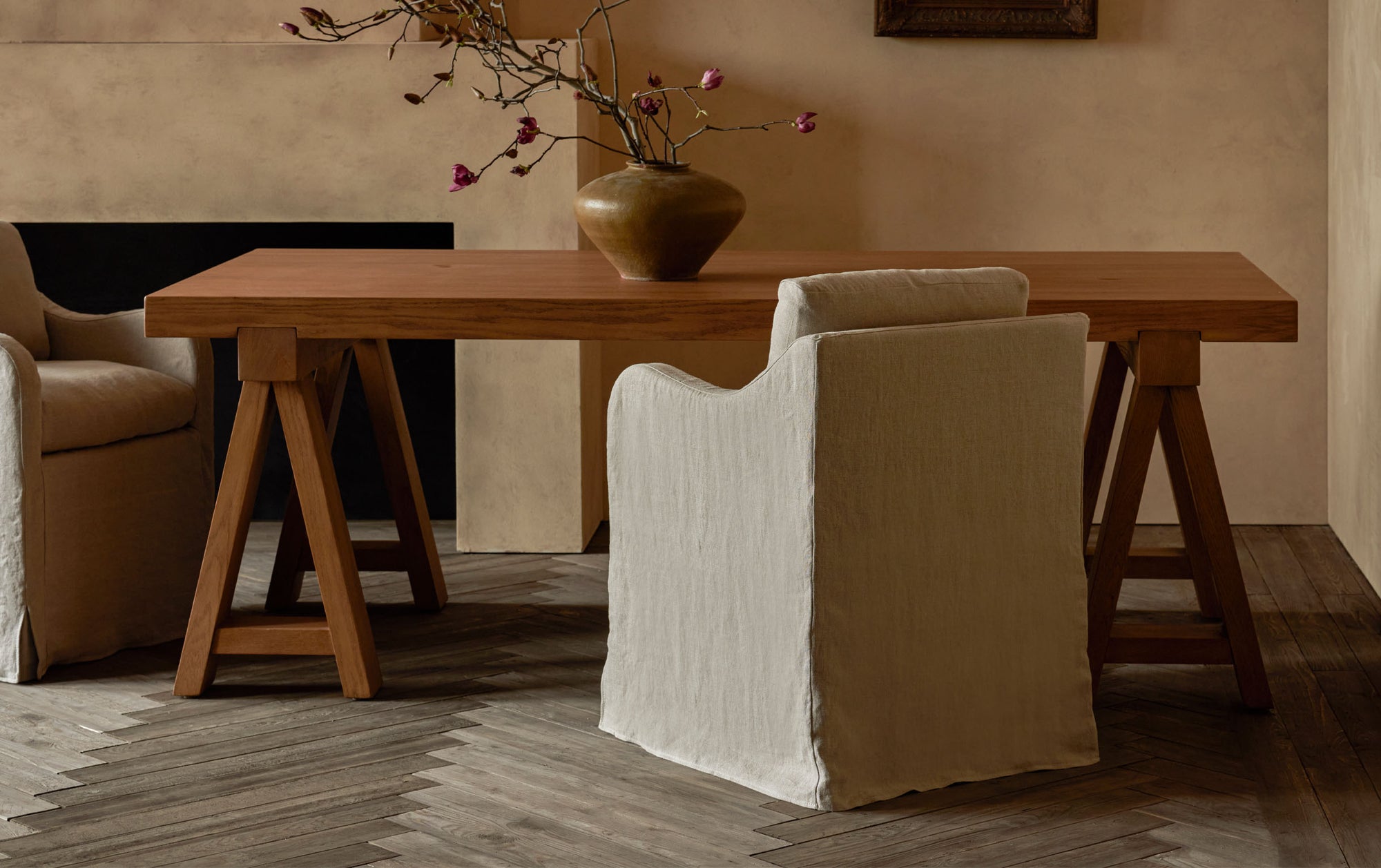 Rylance Dining Table in Tinted Oak, a golden, wheat-colored 100% American red oak, decorated with a vase of flowers and placed in a room with two Esmé Dining Chairs