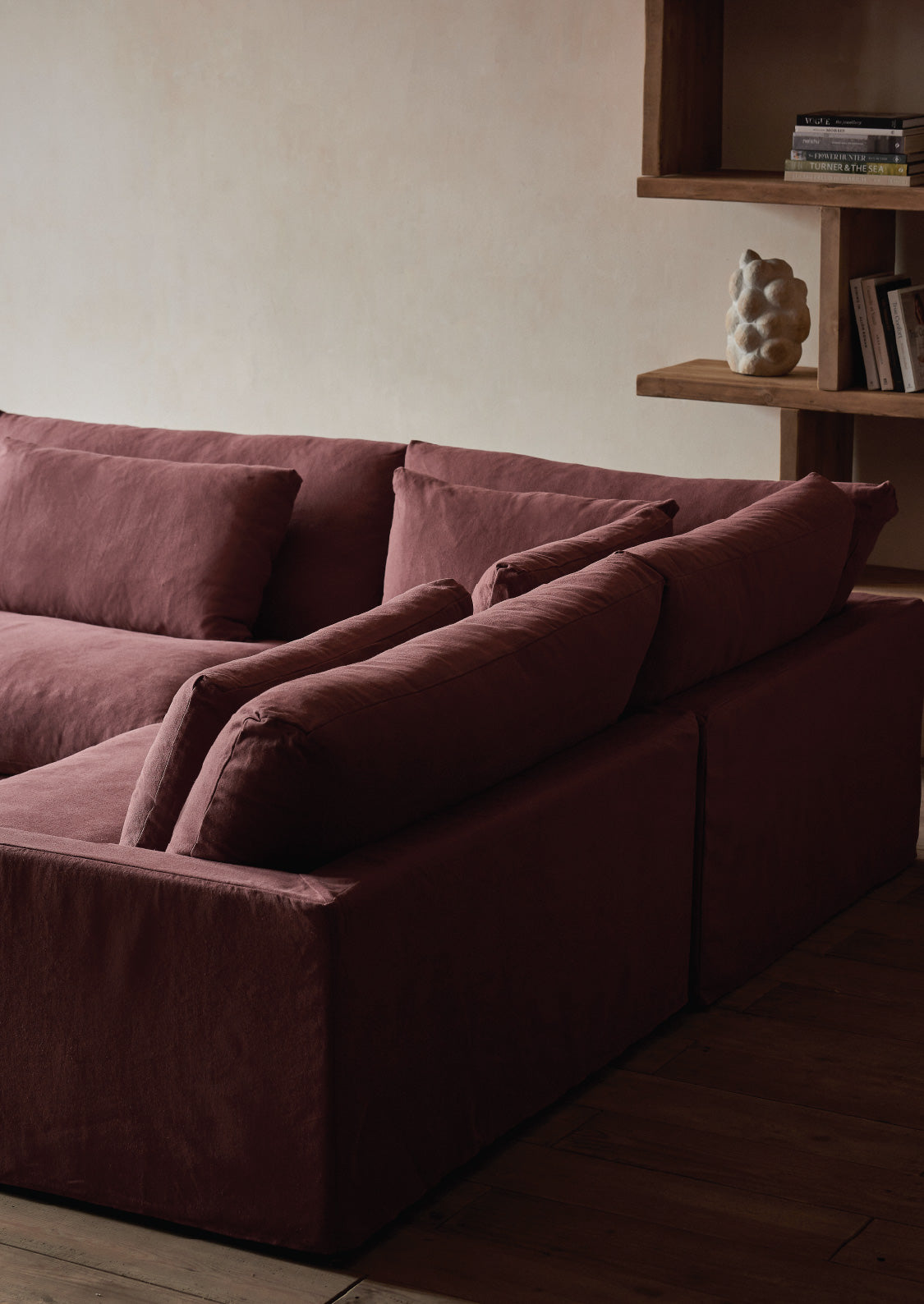 sixpenny amelia sectional sofa in a room with a wooden shelf and decor items.