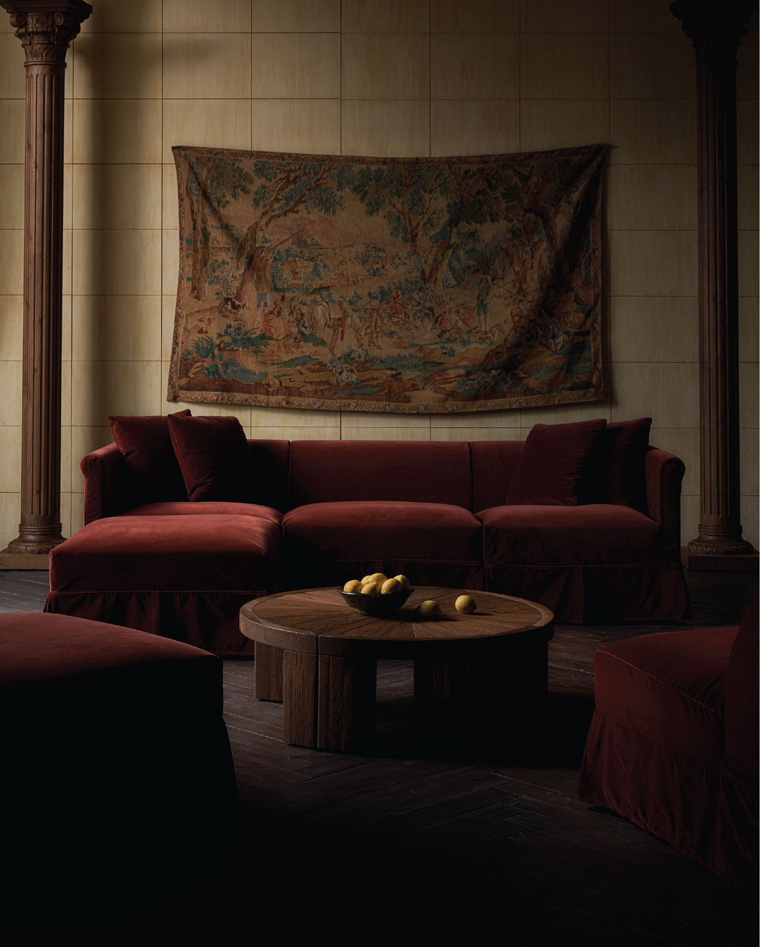 Dark living room with sixpenny dahlia sectional sofa, tango coffee table, and tapestry on the wall.