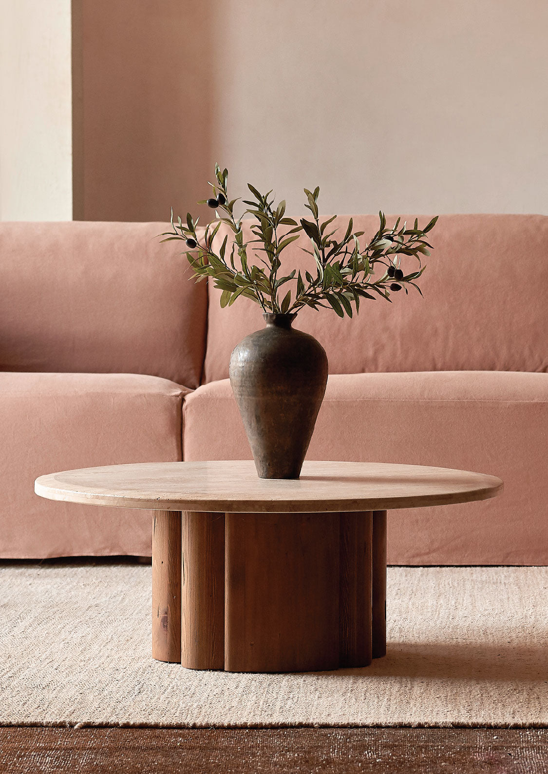 sixpenny enzo coffee coffee table with a vase and branches in front of a pink sofa.