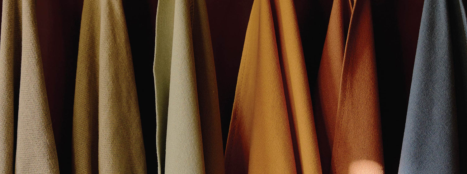 Row of draped sixpenny fabric swatches in various colors on a dark background
