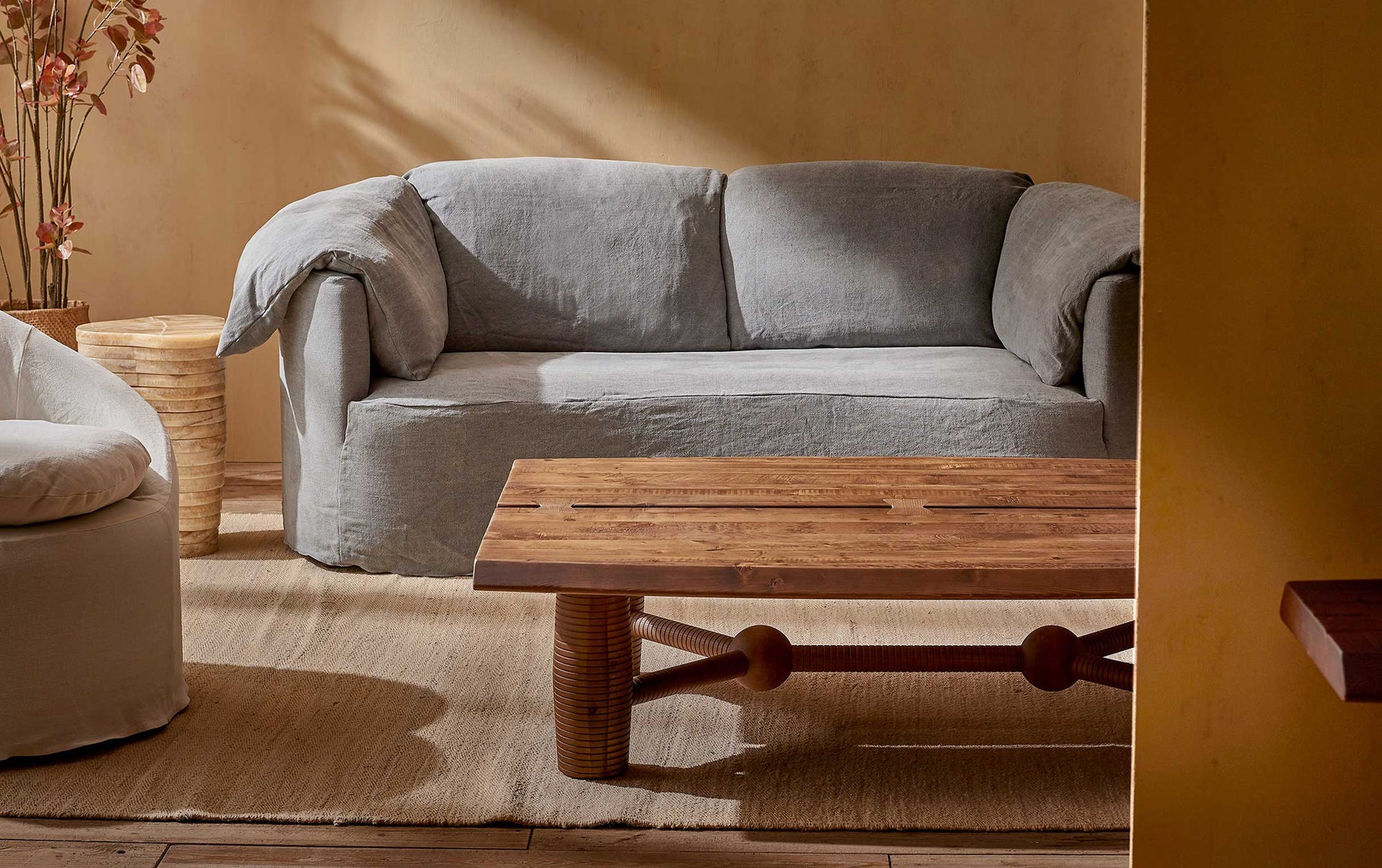 A Zenia Coffee Table in Heritage Pine is placed in front of the Loula Sofa and Ozzi Chair