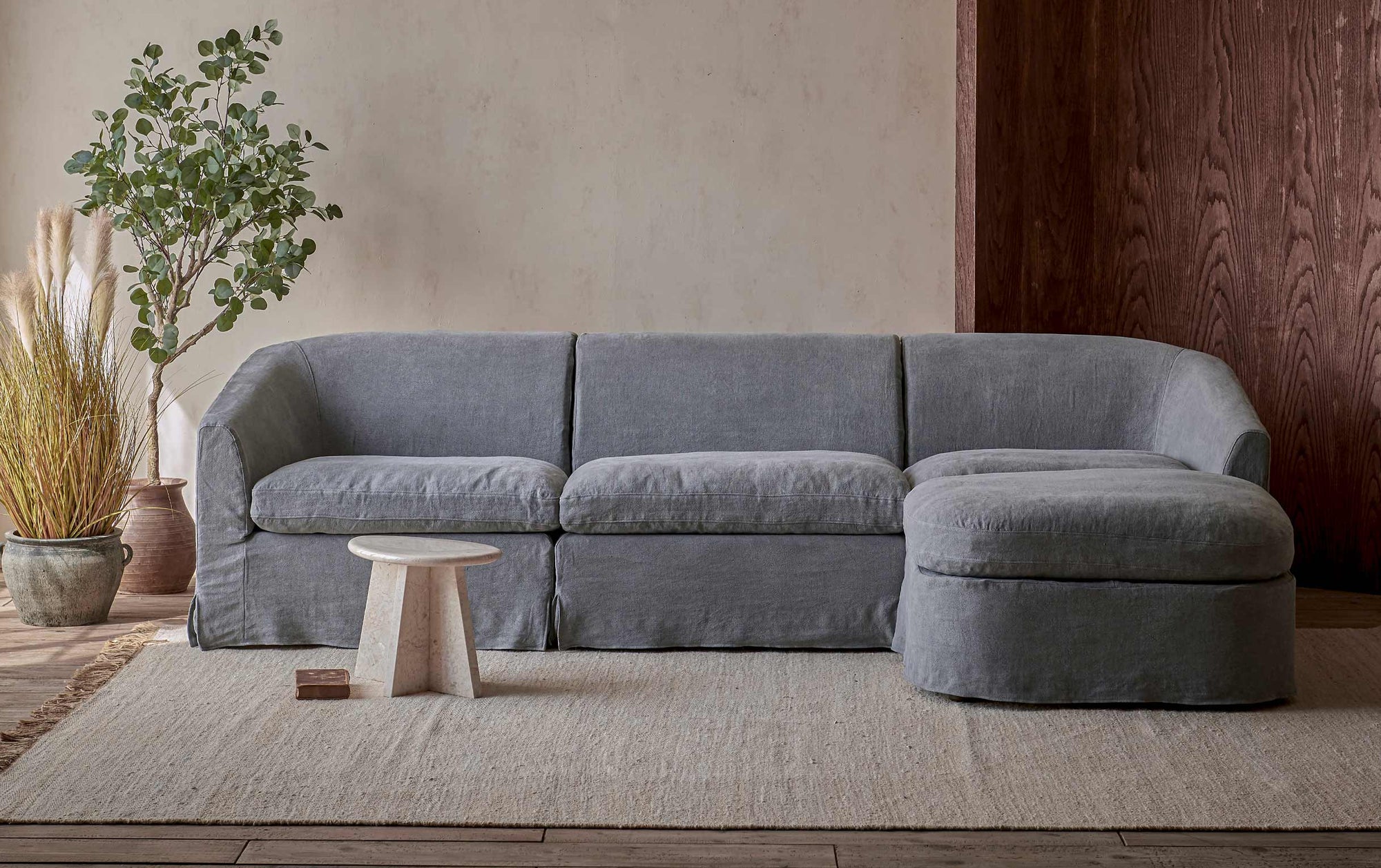 Ziki 4-Piece Chaise Sectional Sofa in Ink Cap, a medium cool grey Light Weight Linen, placed in a room beside potted plants and a side table