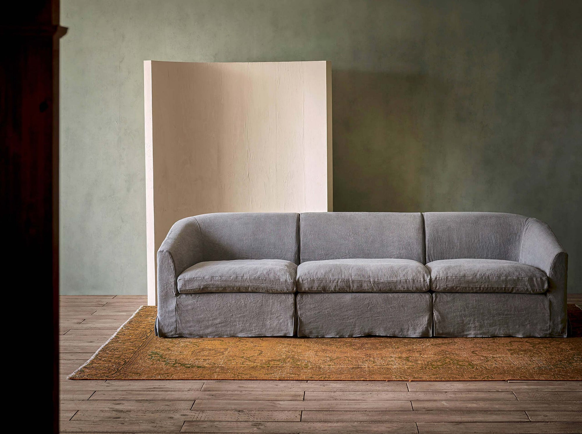 Ziki Sectional Sofa in Ink Cap, a medium cool grey Light Weight Linen, placed in a room with a console table