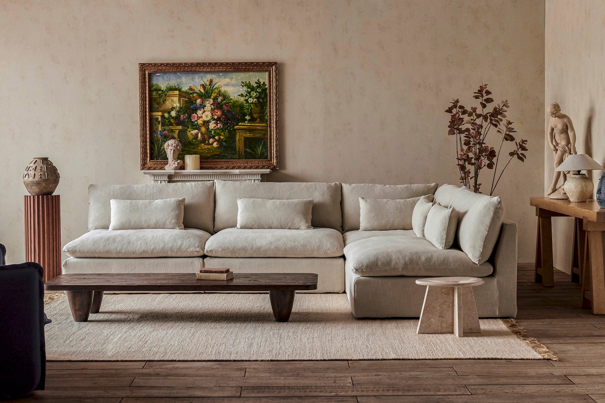 Aria Grande L-Shape Sectional Sofa in Warm Oatmeal, a light warm beige Medium Weight Linen, placed in a decorated room with the Theo Coffee Table