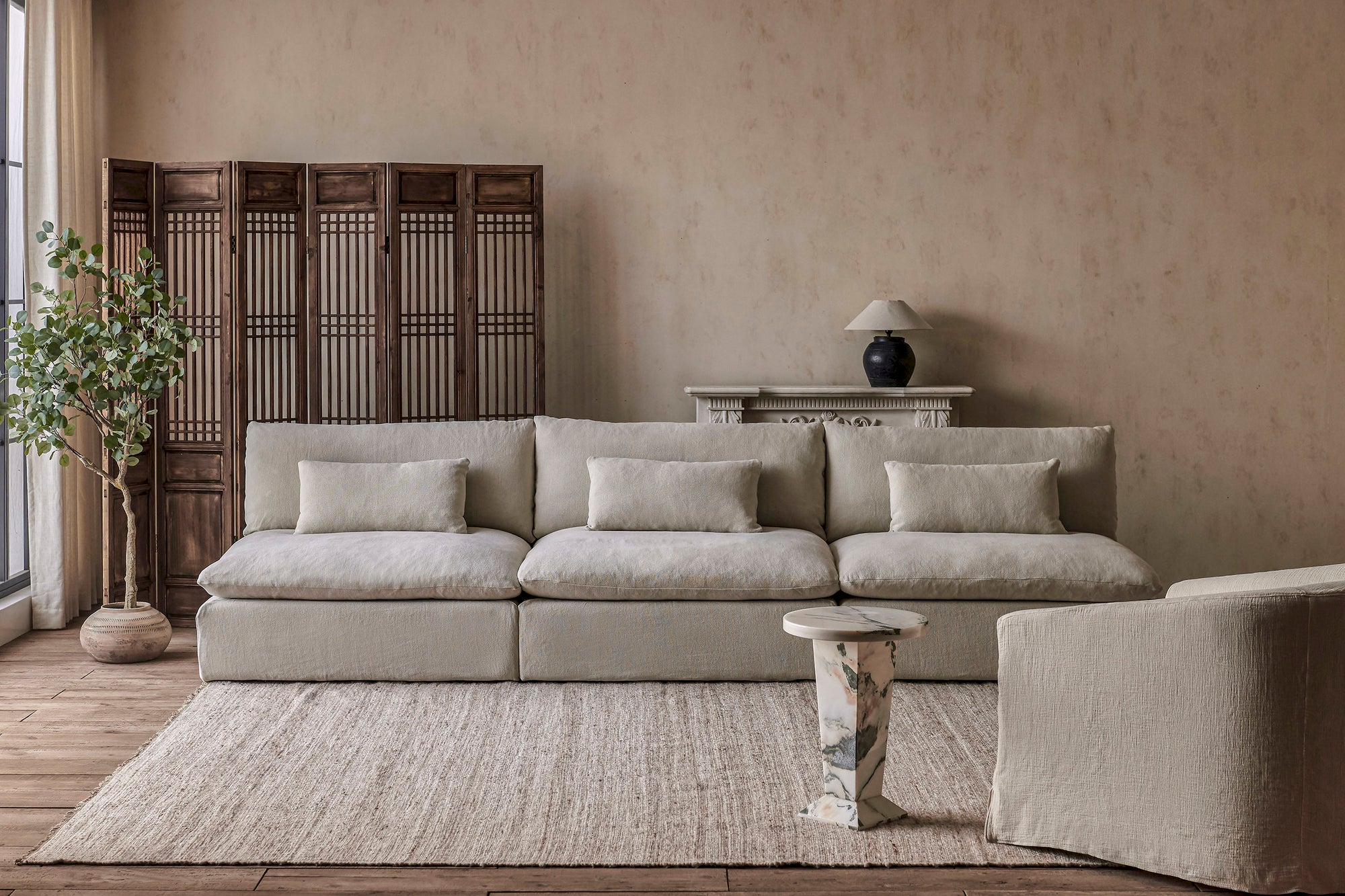 Aria Grande Sectional Sofa in Warm Oatmeal, a light warm beige Medium Weight Linen, placed in a room alongside the Ziki Chair and home decor