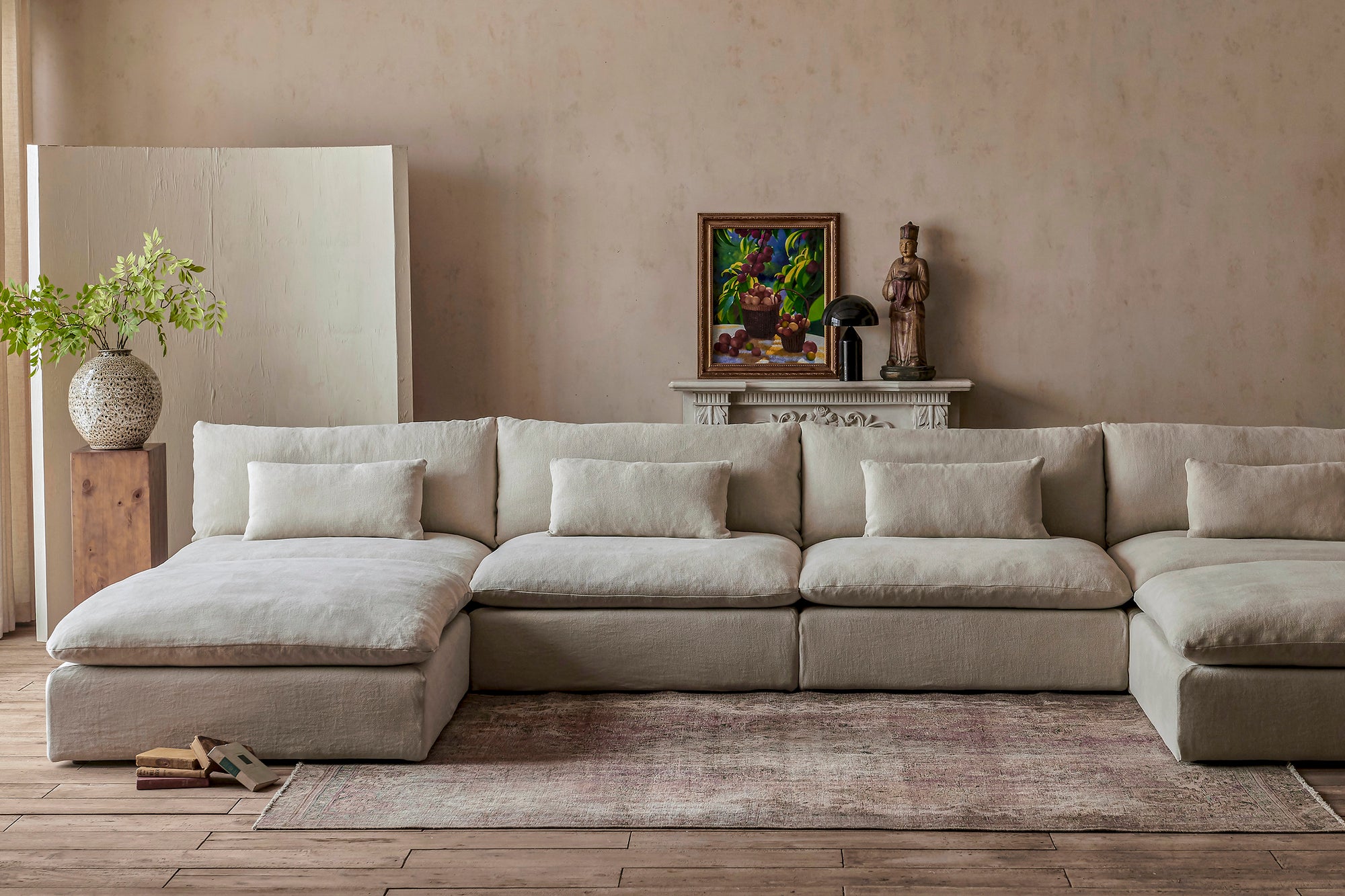 Aria Grande U-Shape Sectional Sofa in Warm Oatmeal, a light warm beige Medium Weight Linen, placed in a decorated room next to a potted plant on top of a pillar