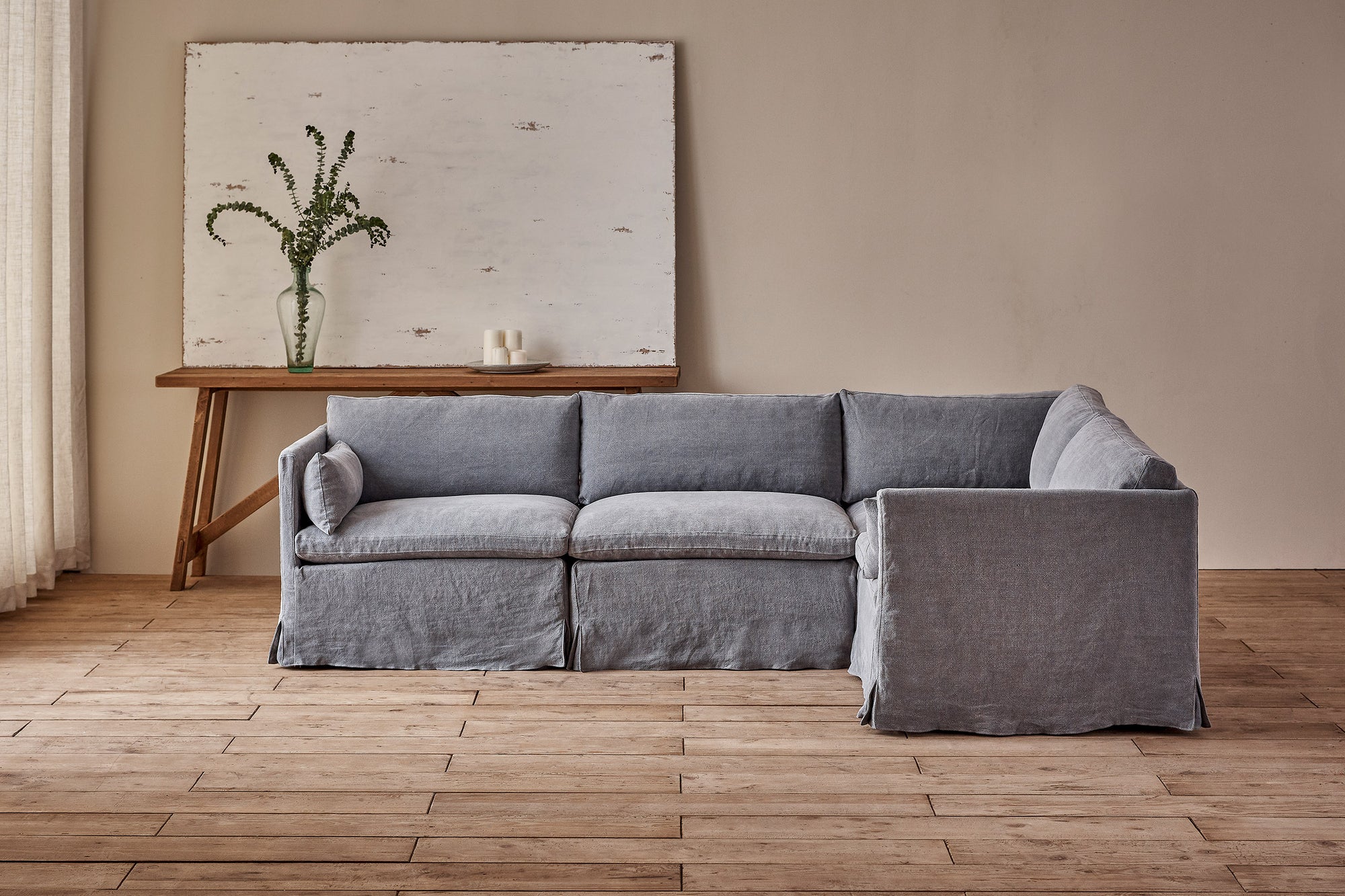 Gabriel L-Shape Sectional Sofa in Ink Cap, a medium cool grey Light Weight Linen, placed in a sunlit room with a console table