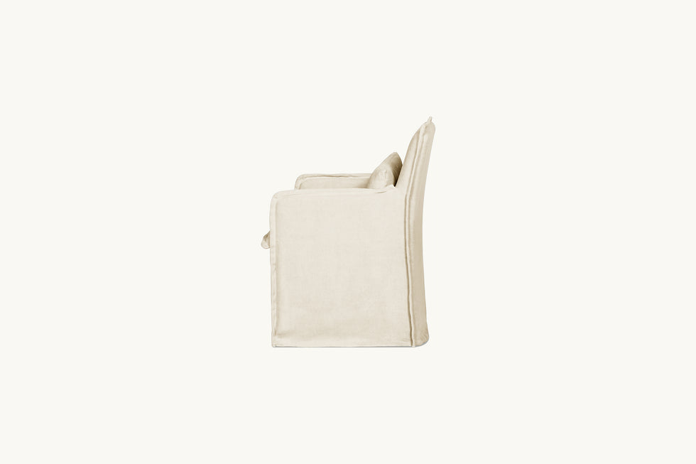 Side view of a Melo Dining Chair in Warm Oatmeal, a light warm beige Medium Weight Linen