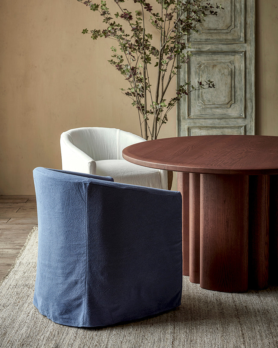 Ziki Dining Chair in Garden Berry, a berry blue Thread-Dyed Cotton Linen, placed next to the Enzo Round Dining Table